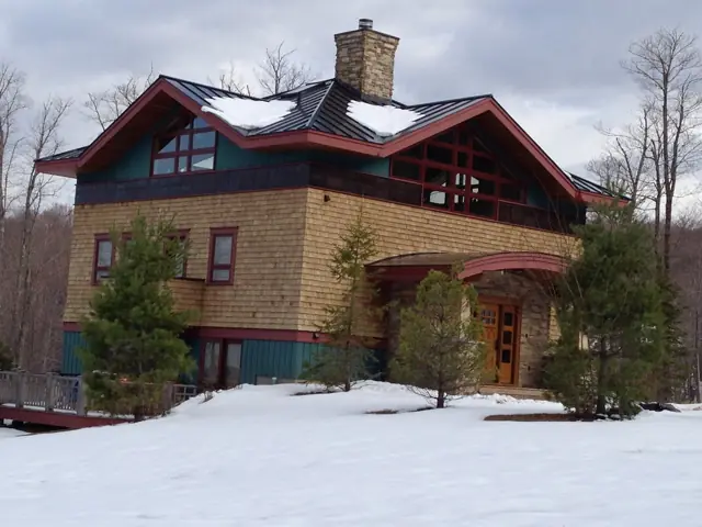 Brick and shingle home with red trim in winter