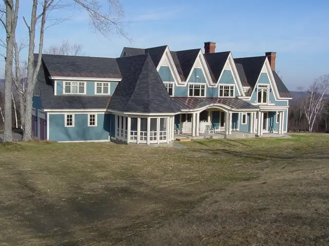 Blue shingle-style home with multiple gables across an open lawn