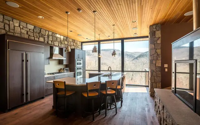Custom kitchen with wood ceiling, stone wall and a glass wall framing mountain views