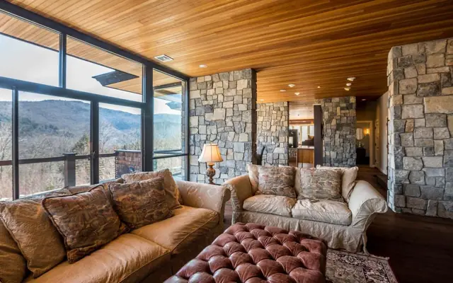 Living room with leather sofas, stone walls and panoramic glass