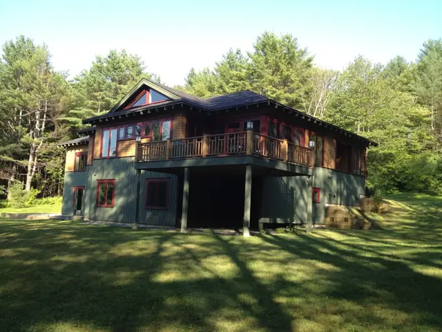 Dark-sided home with a full-width porch on a lawn