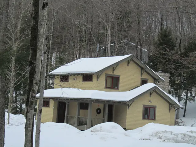 Yellow farmhouse with dormers in deep snow