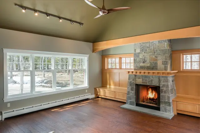Room with a stone fireplace, built-in benches and large windows